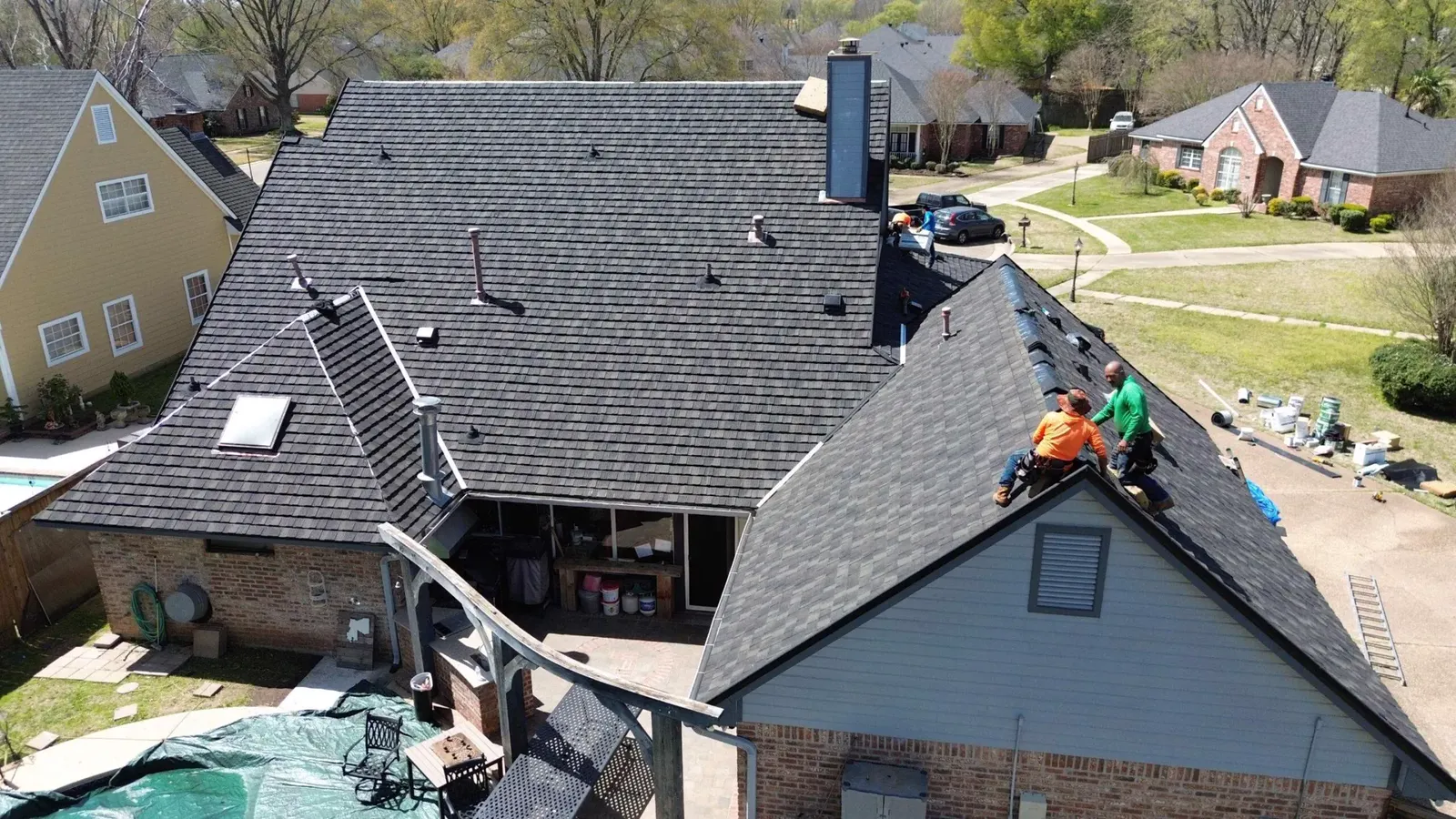 Drone view of our crew installing a new dark shingle roof on a suburban house