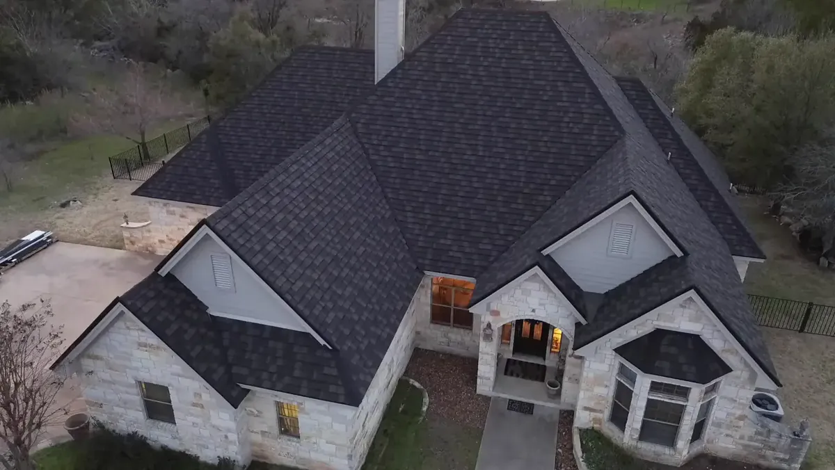 New dark shingle roof on a stone house, seen from a drone
