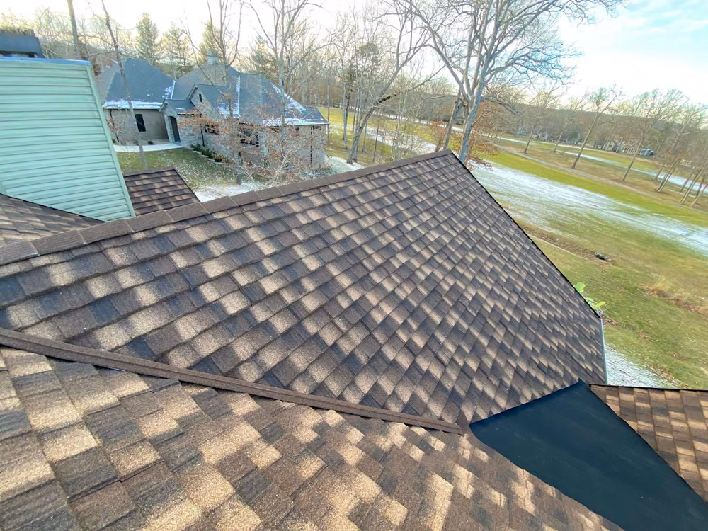 Brown stone-coated steel shake panels and a metal trim piece where a lower roof meets the upper section