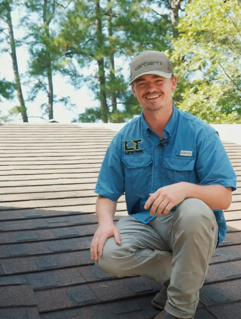 Jon Speer, sales manager at Lifetime Construction Builders, kneeling on a roof