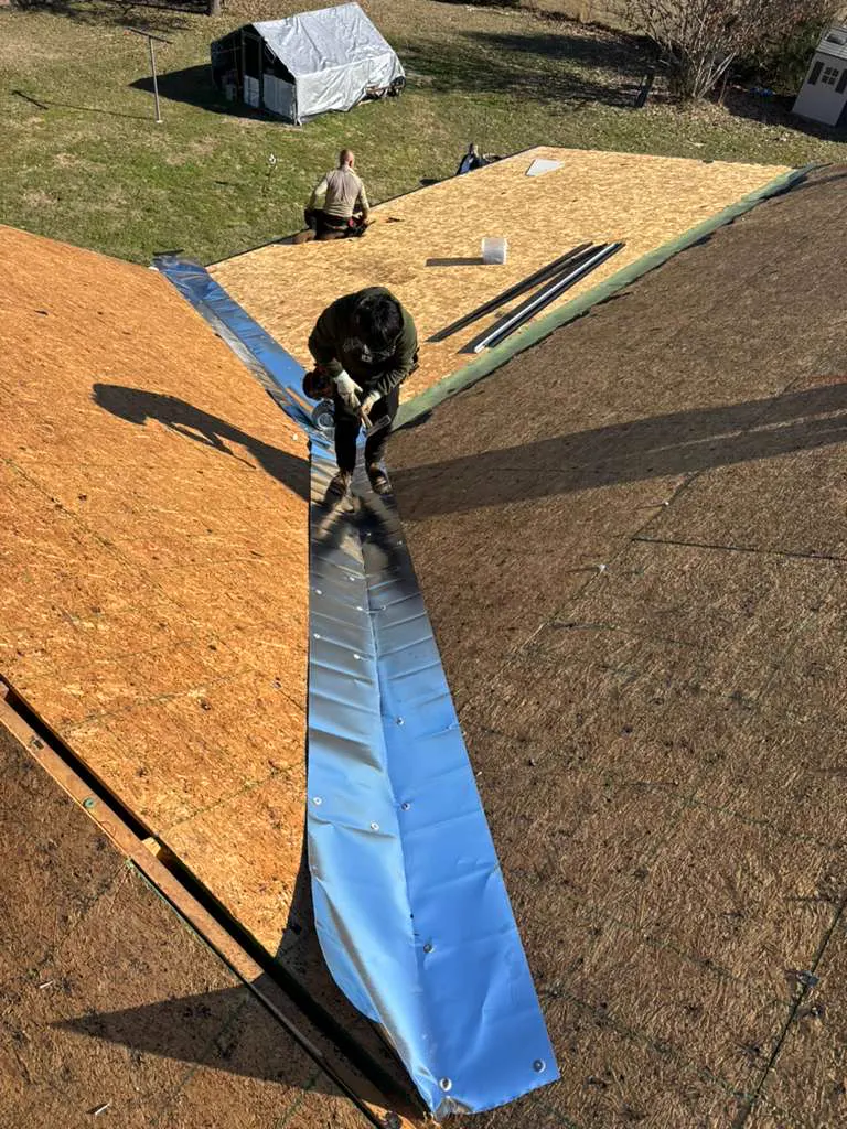 Roofer installing metal valley flashing over new decking